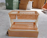 A two-tier peach and white plastic dish drying rack on a cardboard box in a warehouse setting.