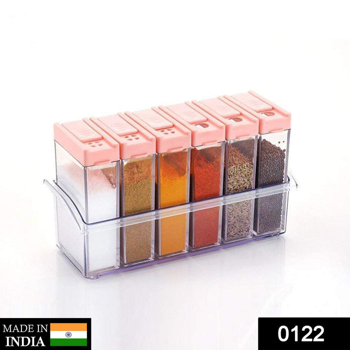 Six clear plastic spice jars with pink flip-top lids in a clear holder, filled with various spices against a white