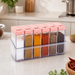 Six clear plastic spice jars with pink flip-top lids in a clear holder, filled with various spices on a kitchen counter.