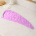 A purple microfiber hair drying wrap towel is laid flat on a white marble countertop next to a brush and cotton swabs.
