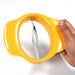 Hand holding the mango slicing tool over a mango, demonstrating its ergonomic design.