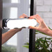 Hands are attaching the illuminated white LED vanity light with four round bulbs to a mirror frame.