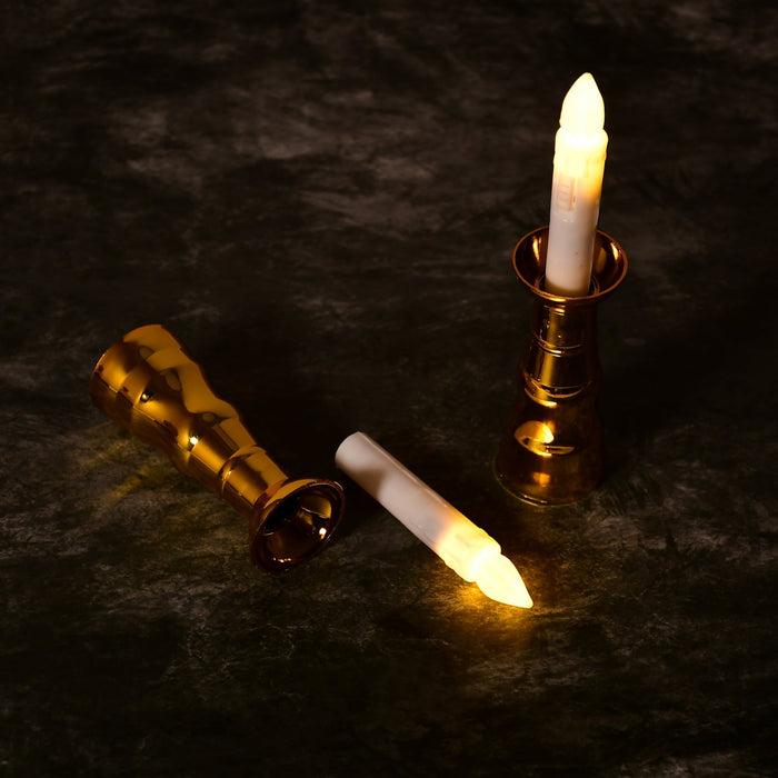 One gold-based LED candle stands upright while another lies on its side with the candle removed.