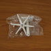 The white plastic components of the rotating hook are sealed in a clear plastic bag on a wooden surface.