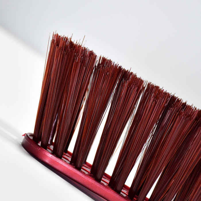 An extreme close-up of the brown bristles of the red and white handled brush, highlighting their texture.