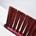 An extreme close-up of the brown bristles of the red and white handled brush, highlighting their texture.