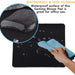 A hand wipes water droplets off a black mouse pad with a blue cloth, highlighting its waterproof surface.