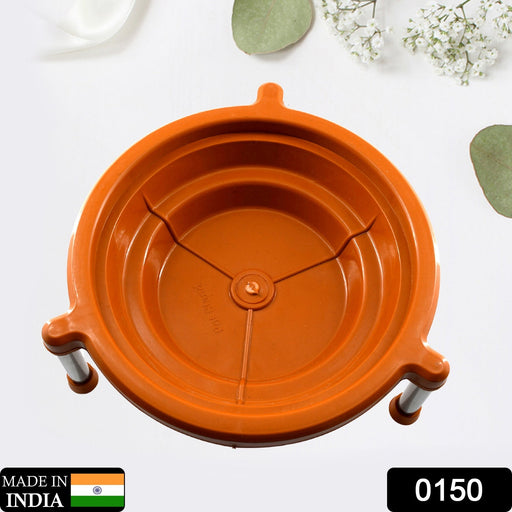 Overhead view of an orange plastic stand with three silver legs, on a white surface with green leaves.