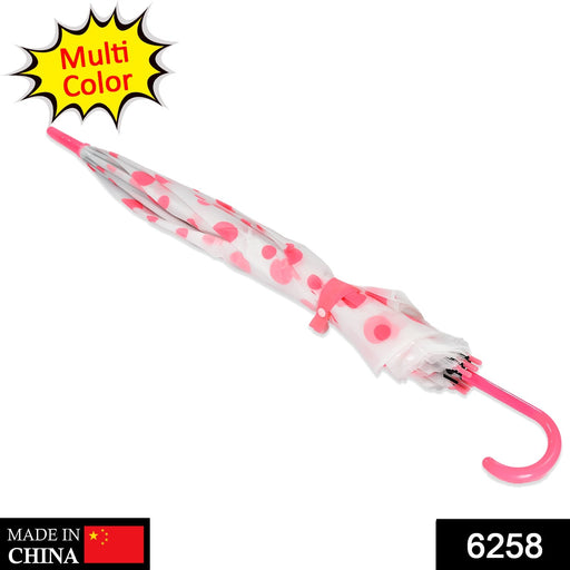 A closed white umbrella with pink polka dots and a hooked pink handle lies diagonally on a white surface.