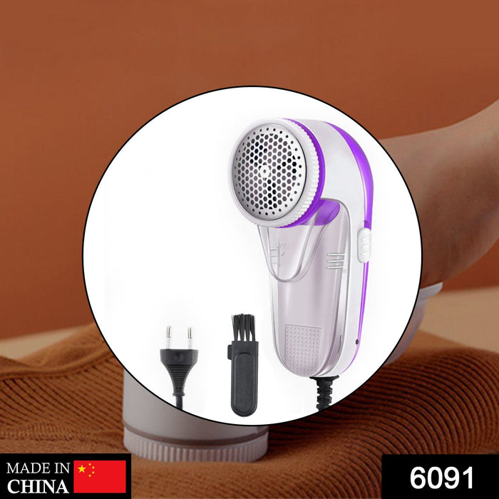 White and purple corded lint remover with a cleaning brush and power plug shown in a circular cutout.