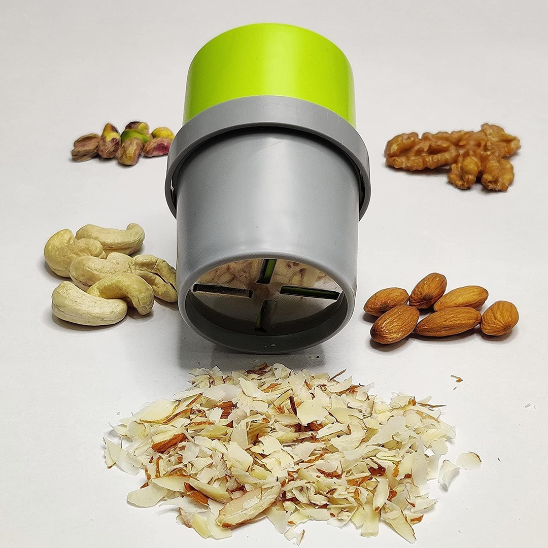A green and gray dry fruit slicer stands upright, surrounded by whole nuts and a pile of sliced almonds.