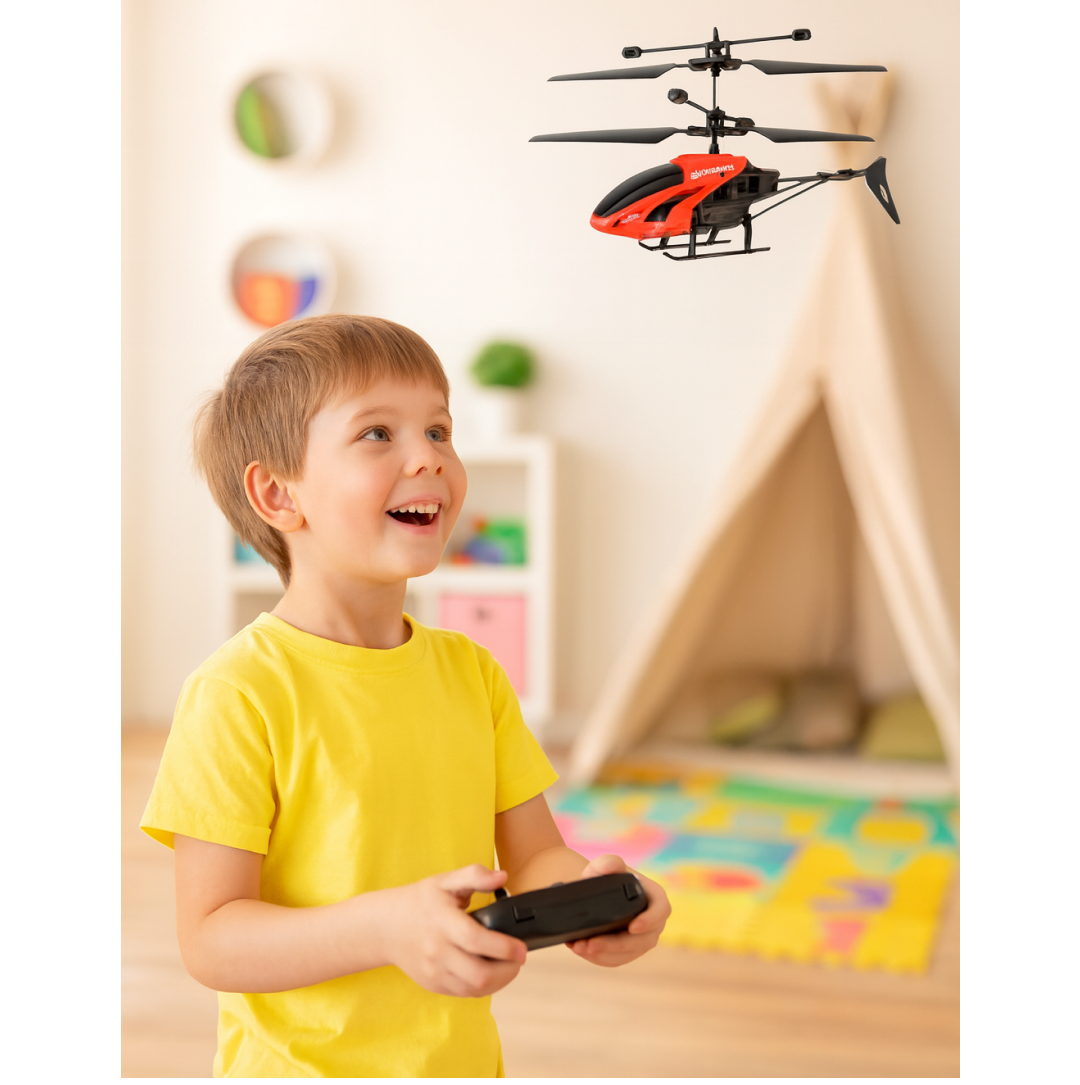 A young boy in a yellow shirt joyfully looking up at a flying toy helicopter with a remote control in his hands.