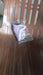 A purple silicone urination funnel is partially visible inside clear plastic packaging, resting on a brown chair.