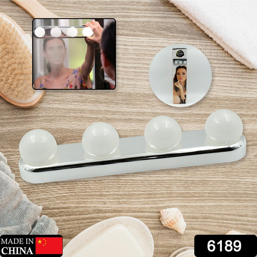 A white LED vanity light with four round bulbs is displayed on a wooden surface with bath accessories and product packaging.