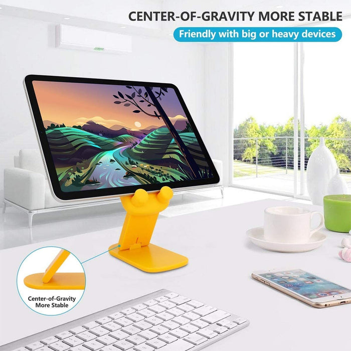 A yellow cartoon duck stand holds a tablet displaying a landscape, with a keyboard and phone on a white desk.