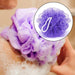 Various colored bath loofah sponges with hanging ribbons.