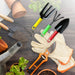 A yellow fork, green cultivator, and red trowel are among various gardening tools and gloves on a wooden surface.
