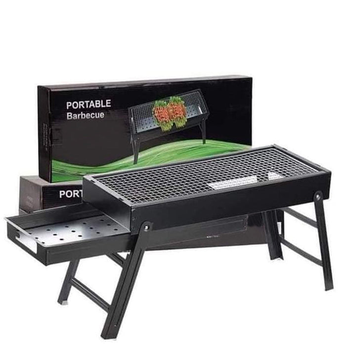 Black portable barbecue grill with an open ash tray and its product box in the background.