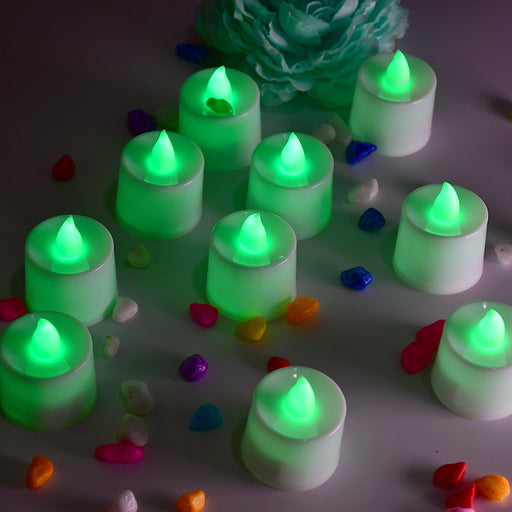 Ten green flameless LED tealights glow brightly on a white surface, surrounded by colorful decorative pebbles and a teal