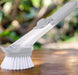 Liquid dispenser dish brush with scraper edge for effective kitchen cleaning.