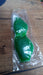 A green gel eye mask is sealed in clear plastic packaging, resting on a wooden surface.