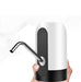 A hand holding a white and black automatic water pump with a silver spout, against a white background with geometric