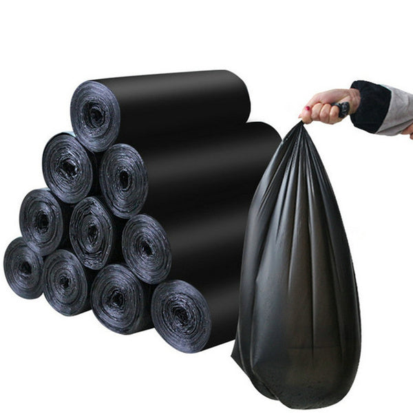 A hand holding a full black garbage bag next to a stack of rolled black garbage bags.