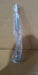 A stainless steel hand whisk wrapped in clear plastic with a red rubber band, against a brown cardboard background.