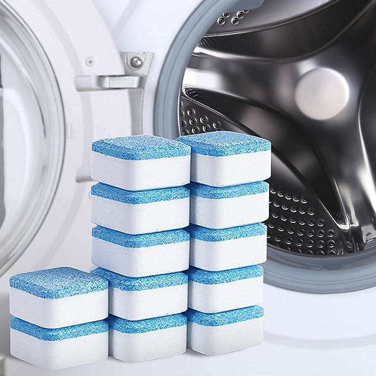 Stacks of blue and white washing machine cleaner tablets in front of a washing machine drum.