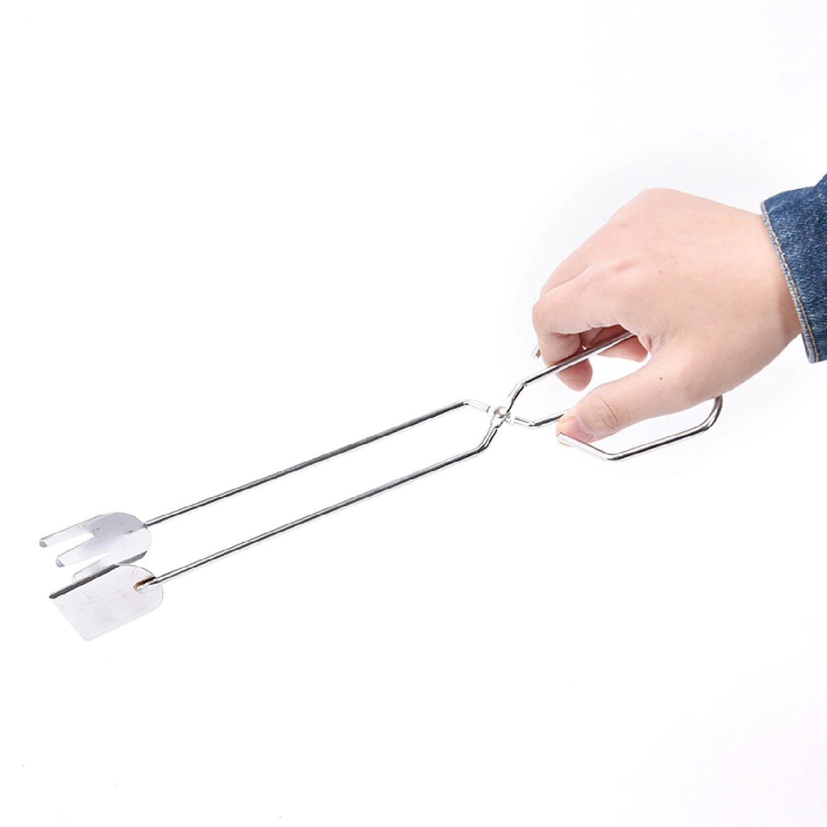 A hand in a denim sleeve holding the shiny silver stainless steel tongs against a plain white background.