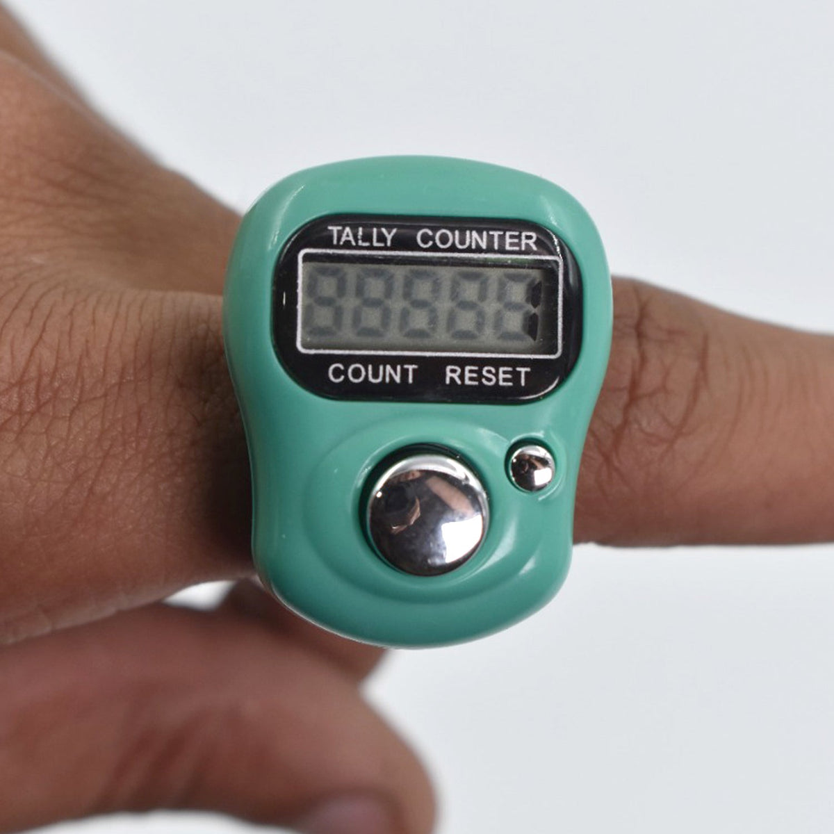 A close-up of a green digital tally counter worn on a finger, showing the display and buttons.