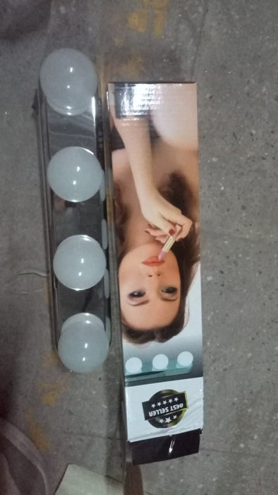 The white LED vanity light with four round bulbs is next to its retail box featuring a woman applying lipstick.