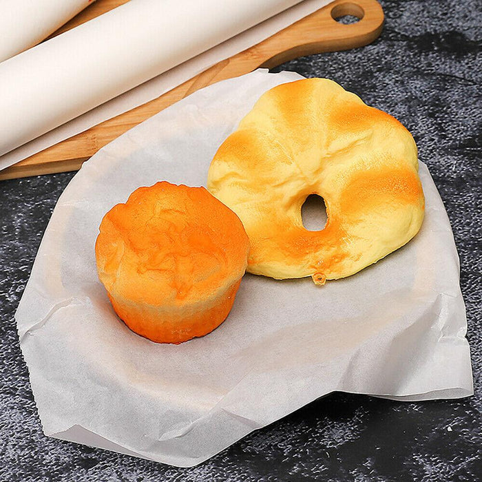 A white sheet of baking paper with a yellow bagel and an orange muffin on a dark surface.
