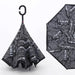 A reverse umbrella with a black and white newspaper print, shown both closed and partially open.