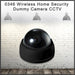 Black dome dummy security camera with a reflective lens, against a brick wall background with three hanging lights.
