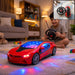 A young boy smiles while playing with a red remote control car that projects colorful lights onto the carpet