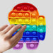 A child's finger presses a blue bubble on a rainbow Among Us character pop-it fidget toy.