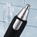 A close-up of the silver trimming head of a black and silver nose hair trimmer with its clear cap removed.