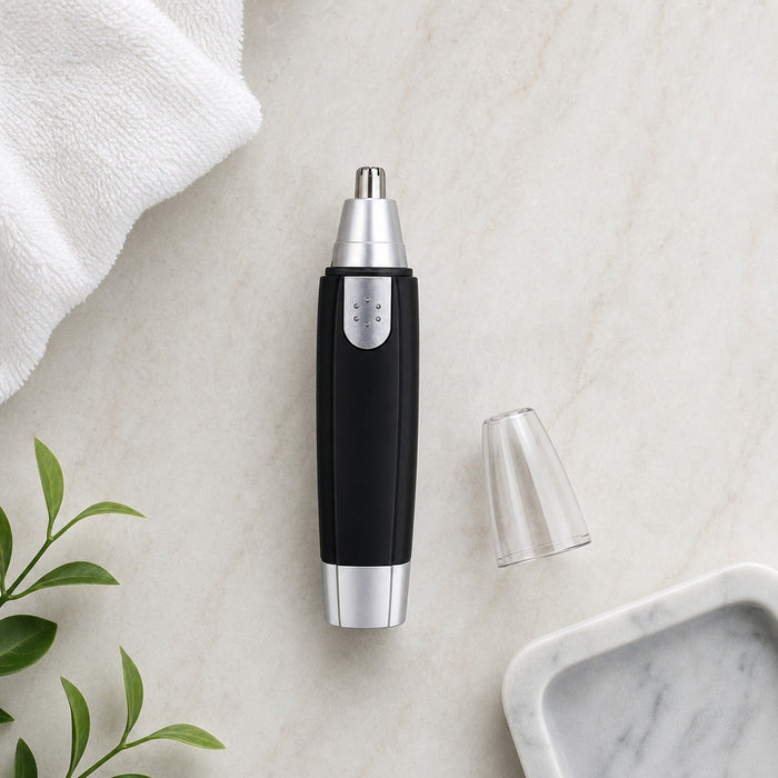 A black and silver nose hair trimmer with its clear cap removed lies on a white marble surface next to a white towel and