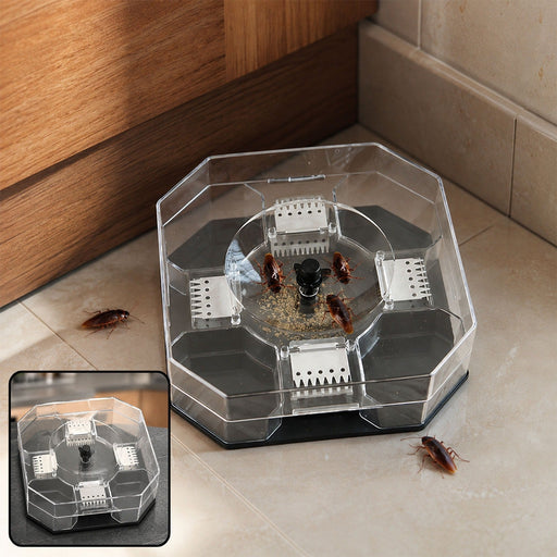 Clear octagonal cockroach trap with bait and several cockroaches on a tiled floor next to a wooden cabinet.